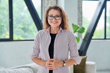 Ofiste kameraya bakan orta yaşlı bir iş kadınının portresi. Gözlüklü 40 'lı yaşlarda kendine güvenen güzel bir kadın. İş yönetimi kariyeri olgun insanlar konsepti