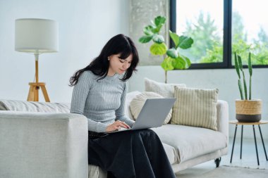 Genç bir kadının portresi kanepede oturmuş, dizüstü bilgisayarında daktilo yazıyor. Üniversite öğrencisi sınava hazırlanıyor, kadın bilgisayar kullanıyor, rahatlıyor sosyal medya blogunu okuyor, internetten alışveriş yapıyor.