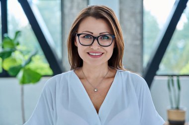 Ofiste kameraya bakan orta yaşlı bir iş kadınının portresi. Gözlüklü, kendine güvenen 40 'lı yaşlarda bir kadın. İş yönetimi kariyeri olgun insanlar konsepti