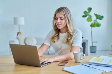 Masasında dizüstü bilgisayarlı ders kitaplarıyla oturan genç bir üniversite öğrencisi. Daktilo yazan defterler. Eğitim, eğitim, bilgi, gençlik kavramı