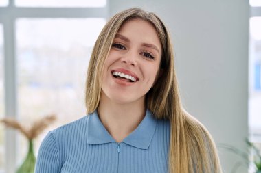 Başarılı bir genç kadının portresi, pencere arkası. Gülümseyen mutlu 20 'li yaşlarda, sarışın, uzun saçlı, kameraya bakan bir kadın. Güzellik, sağlık, yaşam tarzı, gençlik kavramı