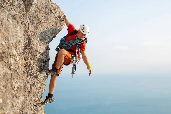 stock image Young male climber climbs a difficult route with a view of the sea at sunset