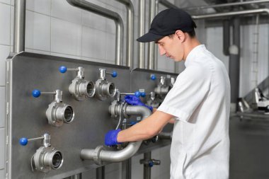 Otomatik süt üretim tesisi. İşçi, çiftlikteki üretim sürecini kontrol ediyor.