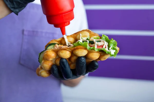 stock image Hong Kong waffles. The cook pours sauce on a sandwich in a waffle