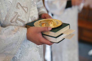 Nikah töreninden önce kilisede bir rahibin elinde tuttuğu alyansın yakın plan fotoğrafı.