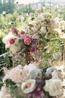 Yeşil çiçek dallarıyla süslenmiş bağcıklara asılı bir çelenk takılı şenlikli bir düğün masası.
