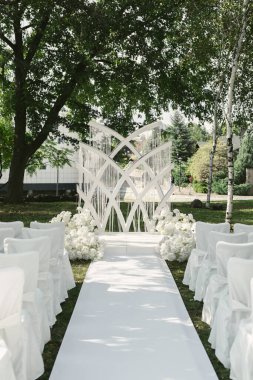 Düğün kemeri beyaz çiçeklerle süslenmiş. Düğün merasiminin lüks alanında fıskiyeli duruyor..