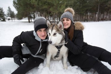 Hoş bir aile, bir erkek ve bir kız ile köpek kış ormandaki. Sibirya husky köpek ile oynamak