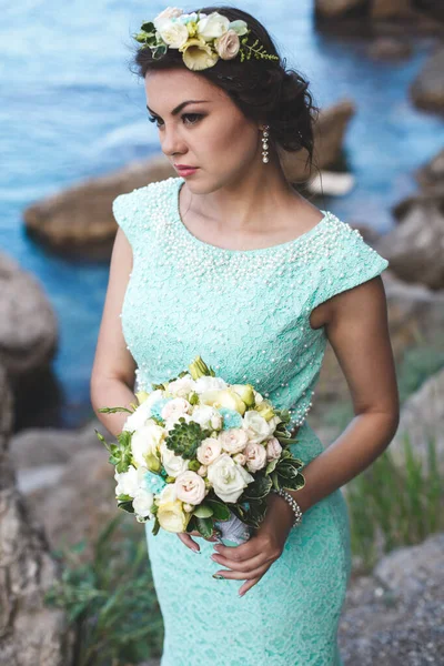 水の近くの山の中で自然の中で花嫁 ドレスの色ティファニー 花束でポーズ花嫁 — ストック写真