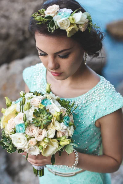 水の近くの山の中で自然の中で花嫁 ドレスの色ティファニー 花束でポーズ花嫁 — ストック写真