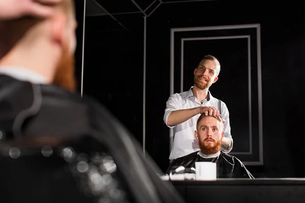 理髪師は理髪店で髪とひげを切ります 美容師ははさみと金属櫛を使用してヘアスタイルを作る — ストック写真
