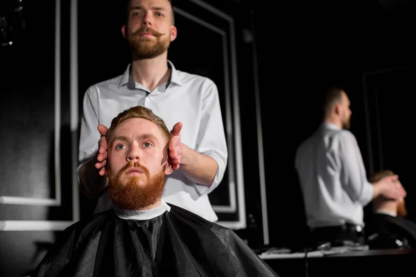理髪師は理髪店で髪とひげを切ります 美容師ははさみと金属櫛を使用してヘアスタイルを作ります 依頼人の仕事に満足してない — ストック写真