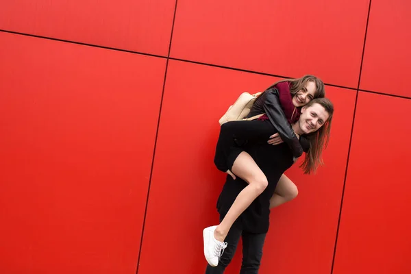 Ein Glückliches Junges Paar Auf Rotem Wandhintergrund Ein Mädchen Springt — Stockfoto