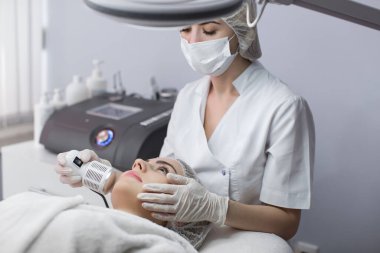 Kozmetoloji. Güzel kadın yüz derisi ultrason yarığı alıyor. Ultrason Cavitation Machine kullanarak Yaşlanma Karşıtı Kozmetik ürünleri alan Kadın Yüze Yakın Çekim. Vücut Bakımı