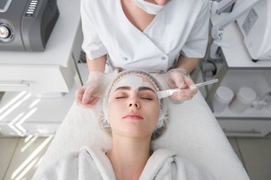 Yüz soyma maskesi, kaplıca güzellik tedavisi, cilt bakımı. Güzellik salonunda güzellik uzmanı bir kadının yüz bakımını alıyor.