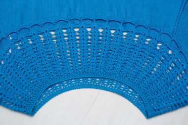 Beyaz arka planda bir çocuk için yün bir elbise örülmüş.