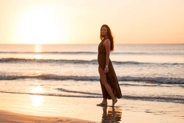 美丽的女人在日落的背景 多彩的黎明掠过大海 无忧无虑的女人在海滩上欣赏日落 快乐的生活 — 图库照片