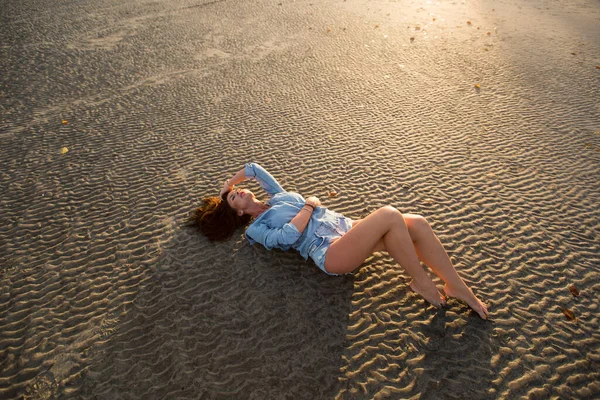 日落时 小女孩躺在沙滩上 — 图库照片