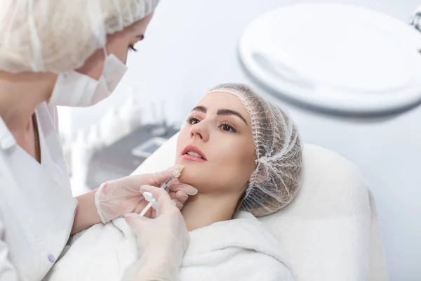 stock image Hands of cosmetologist making injection in face, lips. Young woman gets beauty facial injections in salon. Face aging, rejuvenation and hydration procedures. Aesthetic cosmetology.