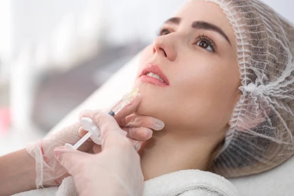 stock image Hands of cosmetologist making injection in face, lips. Young woman gets beauty facial injections in salon. Face aging, rejuvenation and hydration procedures. Aesthetic cosmetology.