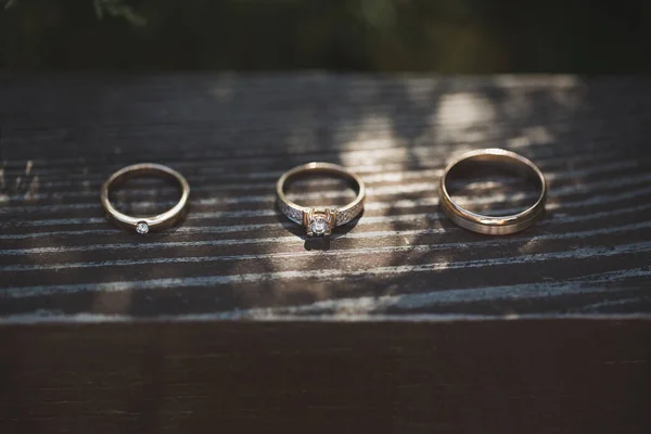木制背景上的三枚戒指 订婚戒指和两个结婚戒指在木制桌子上 白色金婚珠宝 — 图库照片