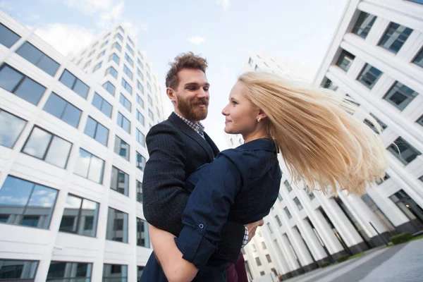 stock image Man and woman hugging and laughing in front of a white building. Bottom view