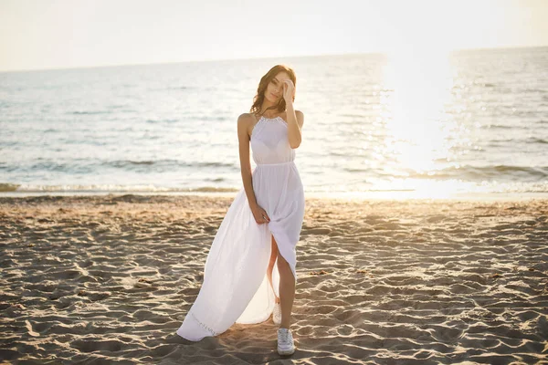 白いドレスとスニーカーを着た美しい女の子の花嫁 ビーチ沿いの日没の散歩 — ストック写真