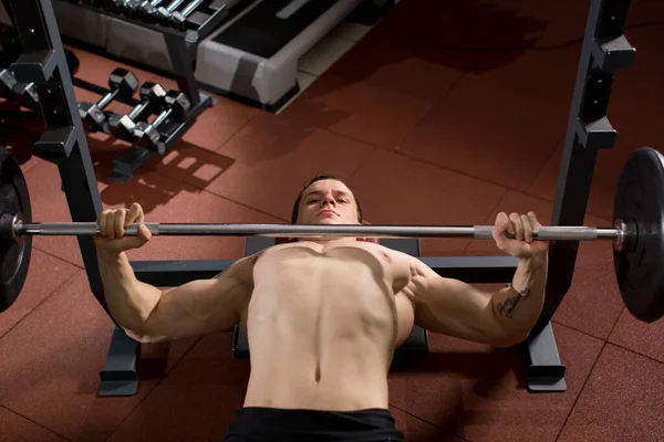 ブルータル運動選手がベンチプレスで筋肉を汲み上げ — ストック写真