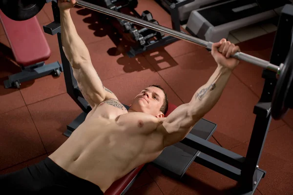ブルータル運動選手がベンチプレスで筋肉を汲み上げ — ストック写真