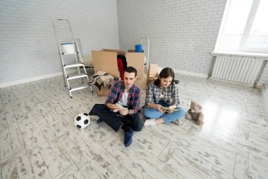 Genç çift yeni dairede yerde otururken para sayıyor.