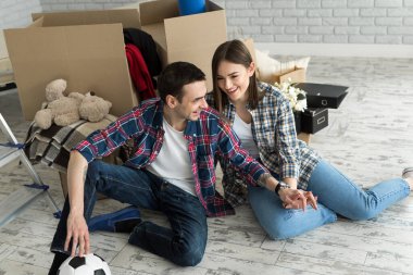 Yeni bir evde genç bir çift büyük kutuların arkasında dinleniyor. Yeni eve taşınma kavramı, birlikte yaşamaya başladık..