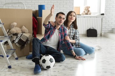 Yeni bir evde genç bir çift büyük kutuların arkasında dinleniyor. Yeni eve taşınma kavramı, birlikte yaşamaya başladık..