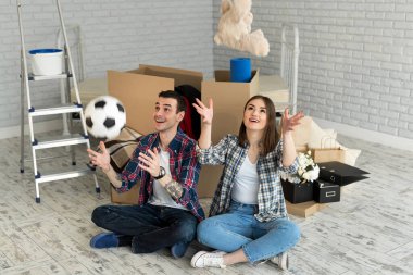 Yeni bir evde genç bir çift büyük kutuların arkasında dinleniyor. Topu at ve oyuncak ayı.