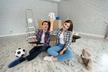 Genç çift yeni dairede yerde otururken para sayıyor.