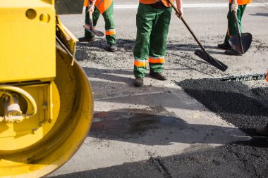 Road Street tamirat sırasında kaldırım makinesinde çalışan işçiler. Sokak yeniden ortaya çıkıyor. Taze asfalt yapısı. Kötü yol.