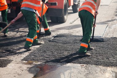 Road Street tamirat sırasında kaldırım makinesinde çalışan işçiler. Sokak yeniden ortaya çıkıyor. Taze asfalt yapısı. Kötü yol.