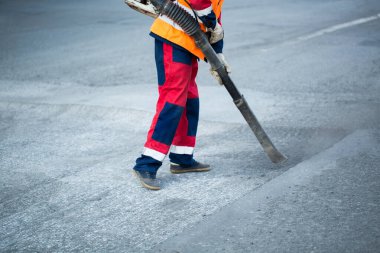 Tramvay pisti yenileme çalışmaları sırasında daha iyi asfalt yapışması için tozu temizleyen yaprak üfleyici işçisi.