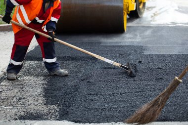 Yol işçilerinin çalışma grubu yolun bir kısmını taze asfalt ile yeniliyor ve tamir için düzleştiriyor..
