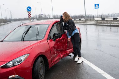 Kadın kazadan sonra kırık bir arabanın yanında duruyor. Yardım çağır. araba sigortası