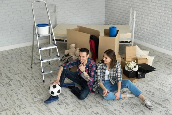 Yeni bir evde genç bir çift büyük kutuların arkasında dinleniyor. Yeni eve taşınma kavramı, birlikte yaşamaya başladık..