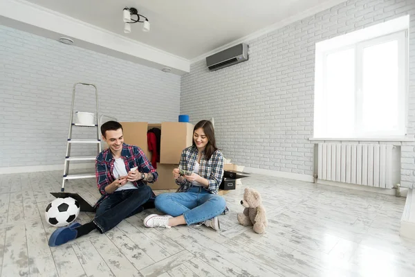 Genç çift yeni dairede yerde otururken para sayıyor.