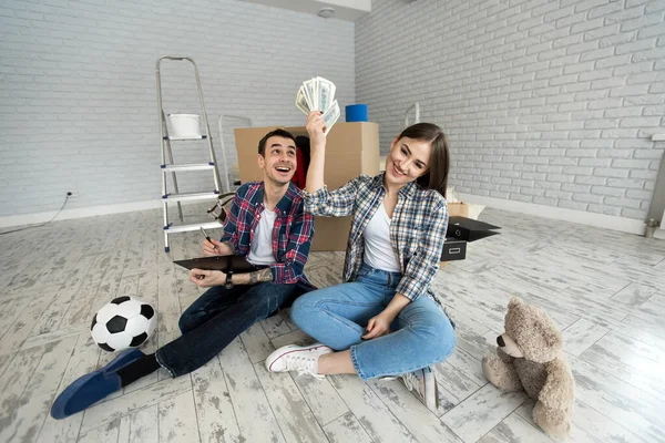 Genç çift yeni dairede yerde otururken para sayıyor.