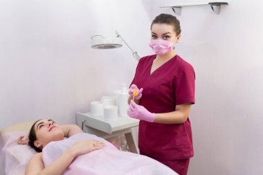 Tüy dökümü için şeker ezmeli bir kozmetolojistin portresi. Shugaring. Konteynırdan bir spatula ile şeker ezmesi. Şekerleme için şeker ezmesi. Güzellik salonunda şekerleme