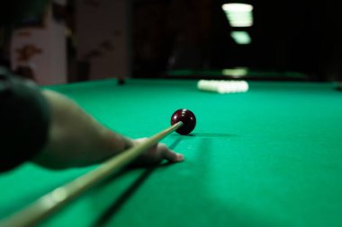 Bilardo topuna bilardo sopasıyla nişan alan bir adam.