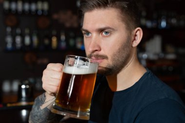 Barda oturan genç adam elinde yarım litre light birayla.