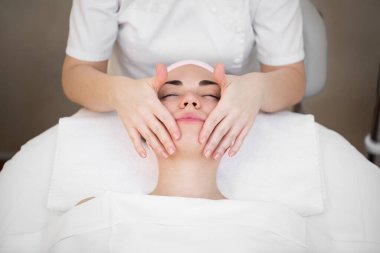 Güzellik uzmanı spa salonundaki genç bir kız için boyun ve omuzlardan profesyonel bir masaj yapıyor. Yukarıdan manzara. Yüz güzelliği tedavisi.