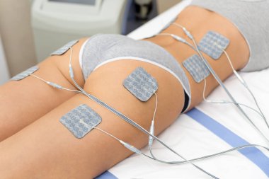 Güzel bir kadın güzellik salonundaki sıkı kalçalarında elektrostimülasyon terapisi, anti-selülit ve anti-yağ terapisi görüyor.