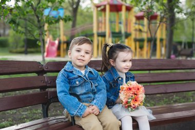 Bir buket çiçekle parkta bir kızla küçük bir oğlanın randevusu..