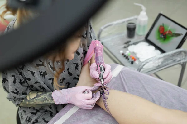 若い女の子の足にカラータトゥーを入れる女性アーティストのクローズアップ タトゥーアーティストは女の子の足にテントウムシを詰めます 女の子のためのタトゥー — ストック写真