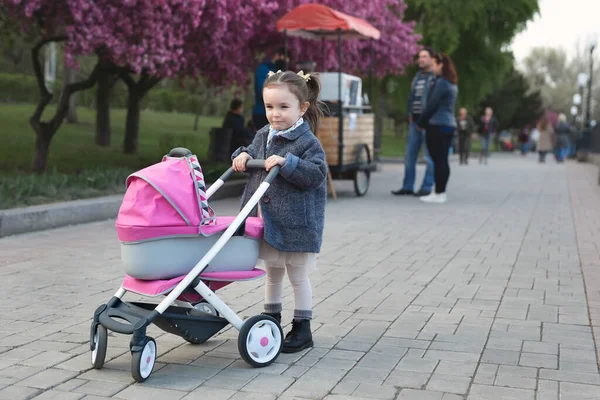 Klein Meisje Een Jas Loopt Het Park Rolt Een Speelgoedwandelwagen — Stockfoto
